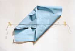 Crumpled blue silk paper pinned with a stretched thread across a pale background, creating a surreal illusion of Crumpled blue silk paper pinned with a stretched thread across a pale background, creating a surreal illusion of depth and fragility. Artwork by Yrjo Edelman.